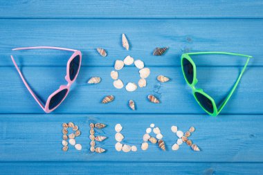 Word relax and shape of sun, sunglasses on blue boards, summer time