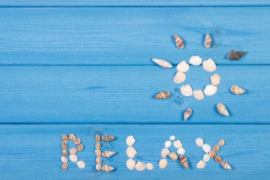 Word relax and shape of sun made of seashells, summer time, copy space for text