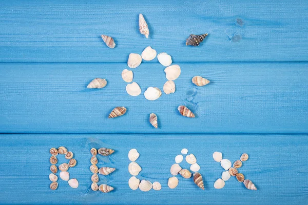 Palabra relajarse y la forma del sol en las tablas azules, la hora de verano — Foto de Stock