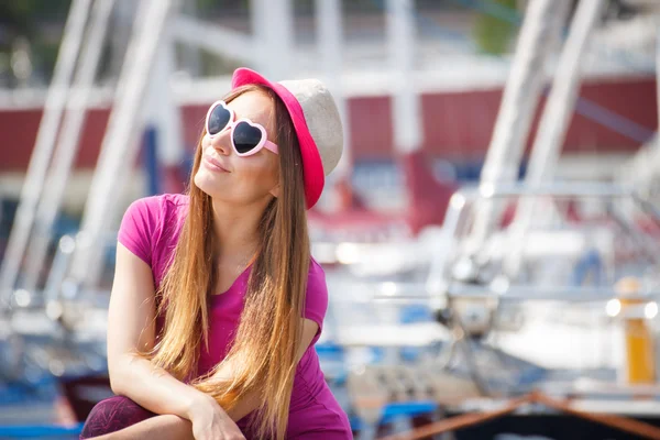 Mujer feliz con sombrero de paja y gafas de sol en el puerto con yate en el fondo, hora de verano — Foto de Stock