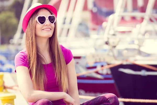 Mujer feliz con sombrero de paja y gafas de sol en el puerto con yate en el fondo, hora de verano — Foto de Stock