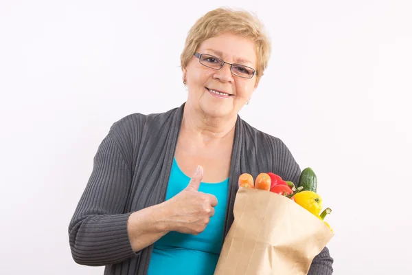 Старшая женщина держит сумку с покупками и показывает большие пальцы вверх, здоровое питание в старости — стоковое фото