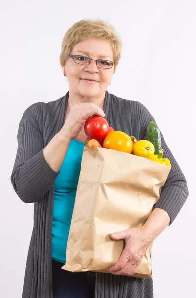 Счастливая пожилая женщина держит сумку с фруктами и овощами, здоровое питание в старости — стоковое фото
