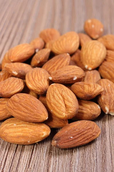 Heap of almonds on wooden background — Stock Photo, Image