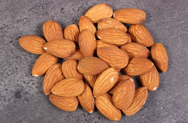 Heap of almonds on concrete structure — Stock Photo, Image