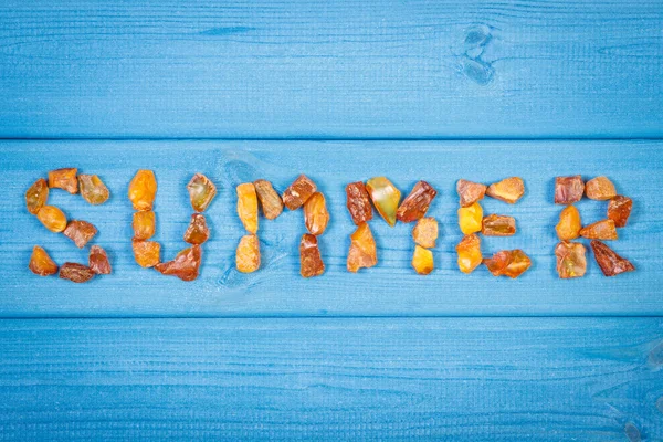 Palavra verão feito de pedras âmbar em placas azuis, hora de verão — Fotografia de Stock