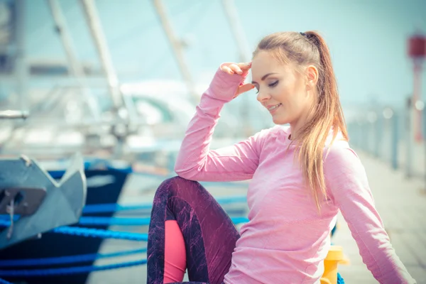 Chica pensativa en ropa deportiva descansando después del ejercicio en el puerto, estilo de vida activo saludable — Foto de Stock