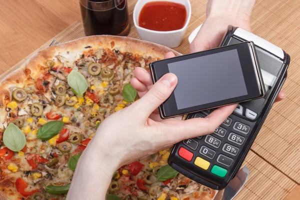 Использование платежного терминала и мобильного телефона с технологией NFC для оплаты в ресторане, вегетарианской пиццы — стоковое фото