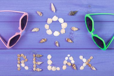 Word relax and shape of sun, sunglasses on purple boards, summer time