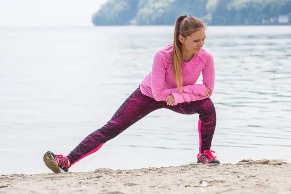 Chica delgada en ropa deportiva haciendo ejercicio en la playa en el mar, estilo de vida activo saludable — Foto de Stock