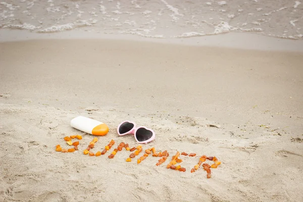 Inscription été, lunettes de soleil et crème solaire sur le sable à la plage, protection solaire, heure d "été — Photo