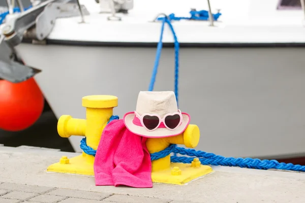 Straw hat and sunglasses in port with yacht in background, travel, summer time — Stock Photo, Image