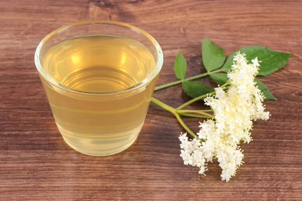 Fresco jugo sano y flores de saúco en tablero rústico — Foto de Stock