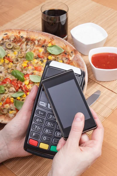 Using payment terminal and mobile phone with NFC technology for paying in restaurant, vegetarian pizza