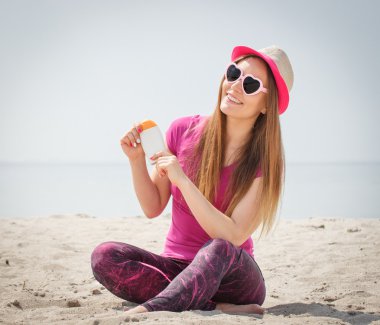 Mutlu kız hasır şapka ve güneş gözlüğü güneş losyonu, güneş Plajı koruma
