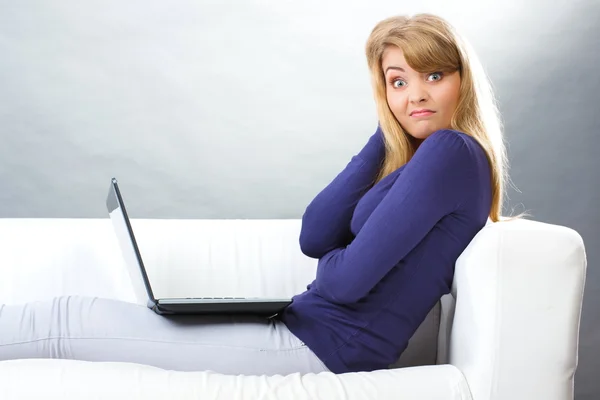 Donna spaventata seduta sul divano e guardando computer portatile, tecnologia moderna — Foto Stock