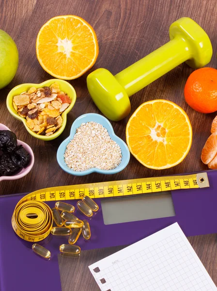 Escala digital con cinta métrica, tabletas, pesas, frutas, muesli, concepto de adelgazamiento — Foto de Stock