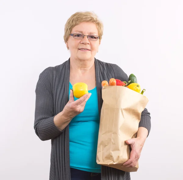 Счастливая пожилая женщина держит фрукты и овощи в мешке, здоровое питание в старости — стоковое фото