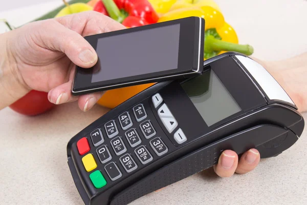 Mano de mujer mayor usando terminal de pago con teléfono móvil, pagando por las compras — Foto de Stock