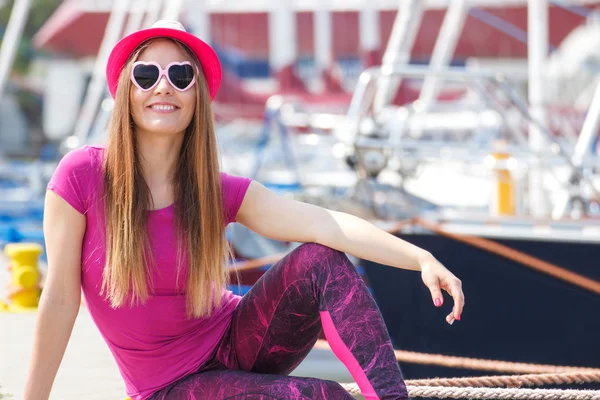 Chica feliz con sombrero de paja y gafas de sol en el puerto con yate en el fondo, hora de verano — Foto de Stock