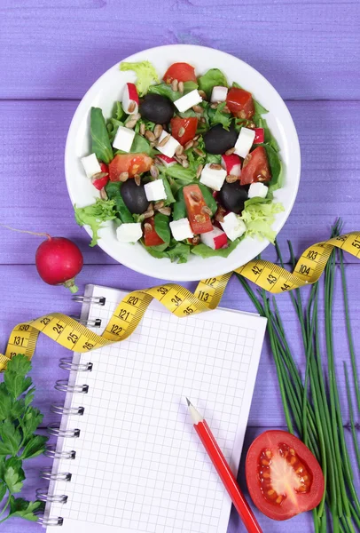 Sałatka Grecka z warzyw, centymetr i Notatnik dla notatki, zdrowej żywności i koncepcja odchudzanie — Zdjęcie stockowe