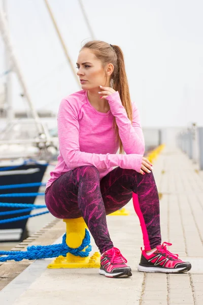 Chica pensativa en ropa deportiva descansando después del ejercicio en el puerto, estilo de vida activo saludable — Foto de Stock
