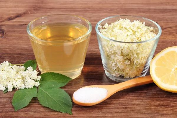 Flores y zumo de saúco, ingredientes para preparar bebidas sobre tabla rústica — Foto de Stock