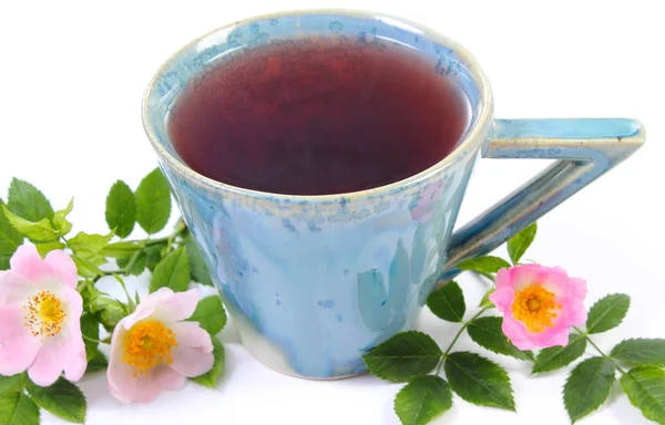 Tasse Tee und wilde Rose Blume auf weißem Hintergrund — Stockfoto