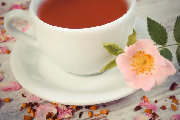老式的照片，杯茶，野生玫瑰花朵上旧仿古木制背景 — 图库照片