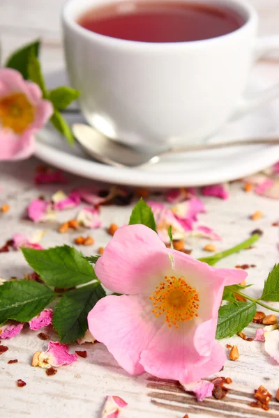 Wild rose bloem en kopje thee op oude rustieke houten achtergrond — Stockfoto