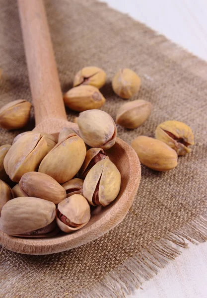 Orzechy pistacjowe z łyżką na biały drewniany stół, zdrowe jedzenie — Zdjęcie stockowe