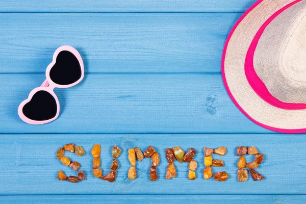 Palabra de verano hecha de piedras ámbar, gafas de sol y sombrero de paja en tablas azules, hora de verano, espacio de copia para el texto —  Fotos de Stock