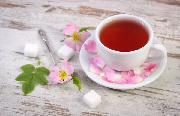 Kopp med te og villroseblomst på gammel, landlig trebakgrunn – stockfoto