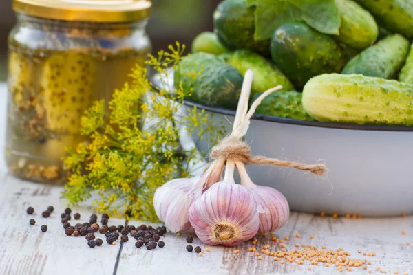 Cucumbers in metal bowl, spices for pickling and jar pickled cucumbers on table — Stock Photo, Image