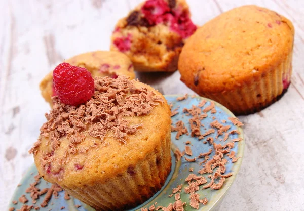 Bagt muffins med hindbær og revet chokolade på træbaggrund, lækker dessert - Stock-foto