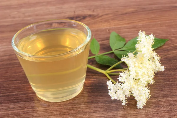 Fresco jugo sano y flores de saúco en tablero rústico — Foto de Stock