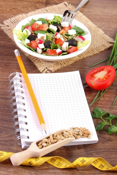 Δροσερή ελληνική σαλάτα με λαχανικά, εκατοστό και το σημειωματάριο για τη σύνταξη την σημειώσεις, υγιεινής διατροφής και αδυνατίσματος έννοια — Φωτογραφία Αρχείου