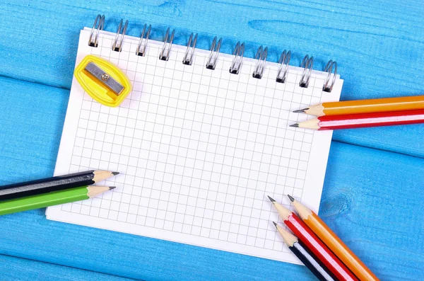 Colorful crayons, sharpener and notepad on blue boards, school accessories, copy space for text — Stock Photo, Image