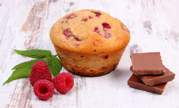 Fresh baked muffins with raspberries and chocolate on wooden background, delicious dessert — Stock Photo, Image