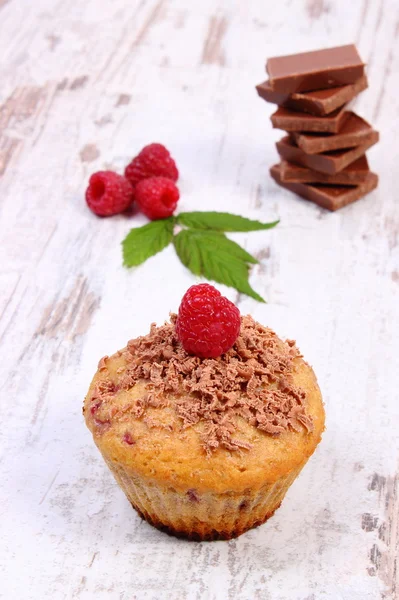 Fresh baked muffins with raspberries and chocolate on wooden background, delicious dessert — Stock Photo, Image