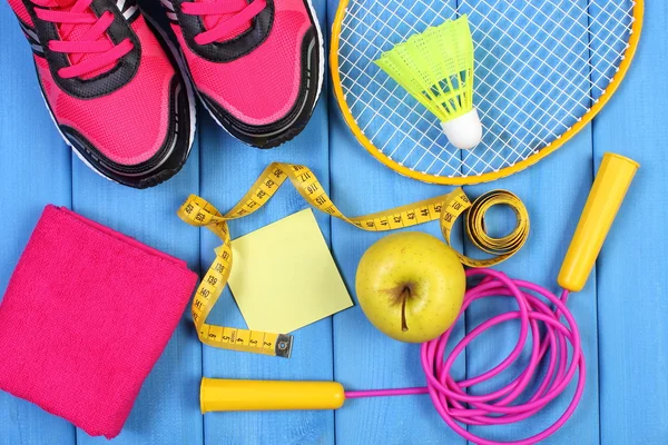 Chaussures de sport roses, pomme fraîche et accessoires pour le sport sur planches bleues, espace de copie pour le texte sur feuille de papier — Photo