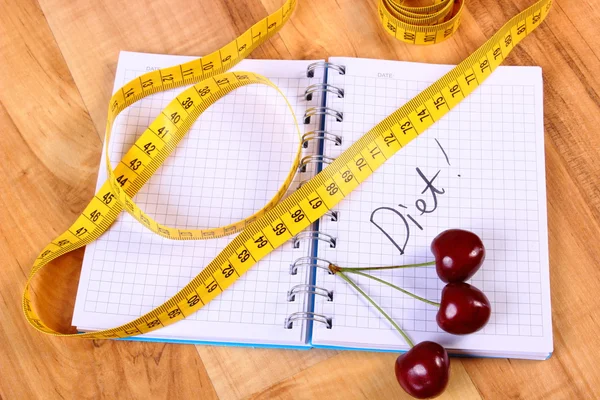 Cherry and centimeter with notebook, slimming and healthy food — Stock fotografie