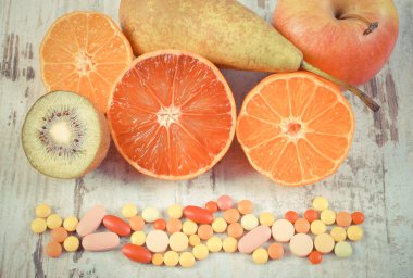 Vintage fotoğraf, Taze meyve ve renkli tıbbi haplar, sağlıklı beslenme ve tıbbi takviyeleri arasında seçim