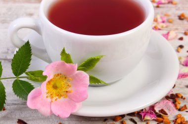 Çay ile eski rustik ahşap arka plan üzerinde yabani gül çiçek