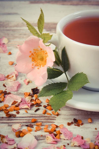 Vintage foto, kopje thee met wild rose bloem op oude rustieke houten achtergrond — Stockfoto