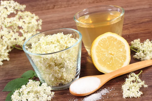 Flores y zumo de saúco, ingredientes para preparar bebidas sobre tabla rústica — Foto de Stock