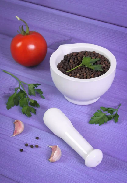 Zwarte peper in de mortel en groenten op paarse boards — Stockfoto
