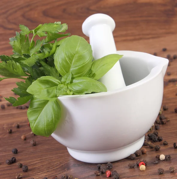 Parsley with basil in mortar and colorful pepper on rustic boards