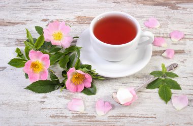 Fincan çay ve eski rustik ahşap arka plan üzerinde yabani gül çiçek