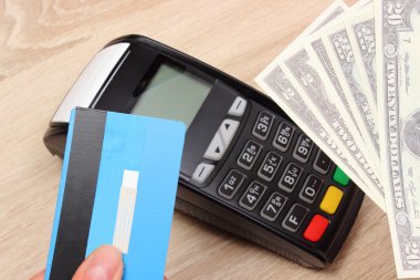 Currencies dollar with credit card and payment terminal in background, finance concept